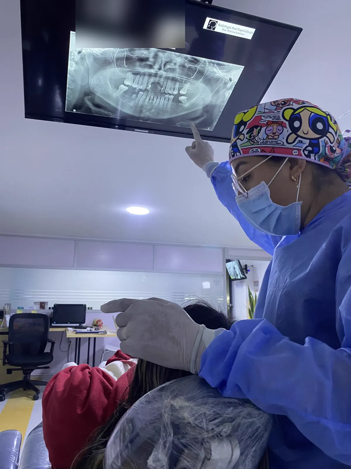 La doctora Natalia señala la radiografía en el televisor